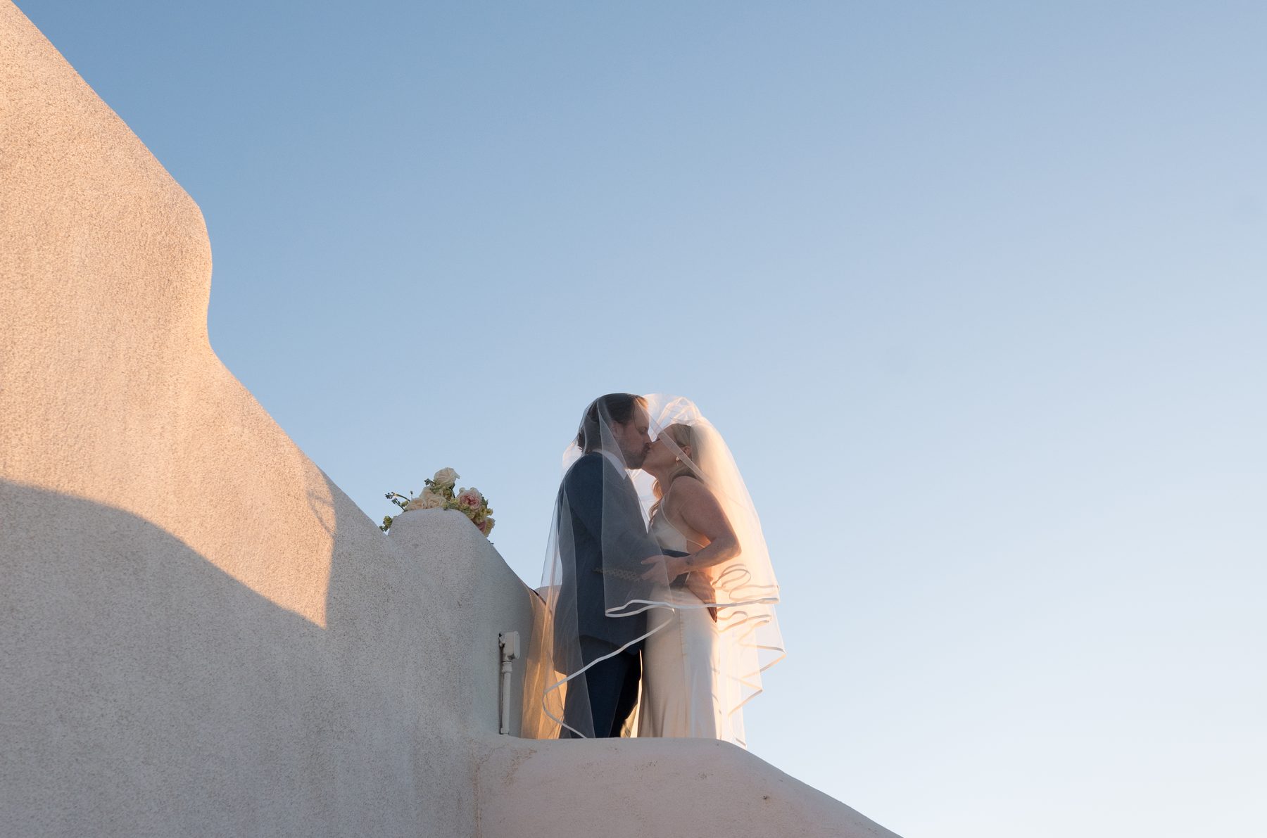 Couple kissing on white adobe rooftop, before Tierra Oscura